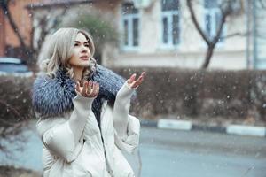 retrato de una hermosa chica en invierno durante la caída de nieve en una calle de la ciudad foto