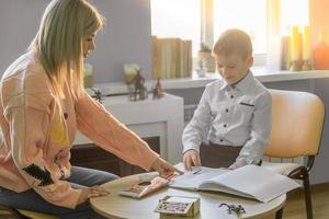 A child psychologist works in his office with a child, a boy of 6-8 years old. The psychologist conducts a conversation with the child, observes how the child draws and what he draws. photo