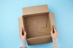 two female hands are holding an empty open box of brown cardboard photo