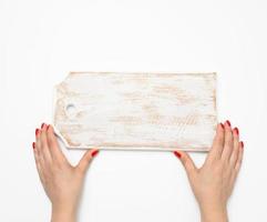 female hand with red manicure holds empty wooden rectangular kitchen chopping board on white background photo