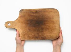 female hand with red manicure holds blank old vintage rectangular kitchen chopping board on white background photo