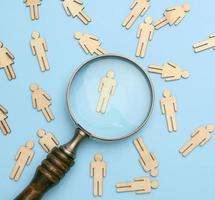 wooden men and a magnifying glass on a blue background photo
