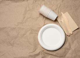 disposable round white paper plates and cups on brown paper background photo