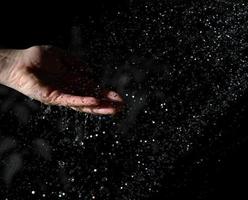 female hand and flying drops of water on a black background photo