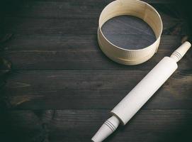 wooden rolling pin and  a wooden round sieve photo