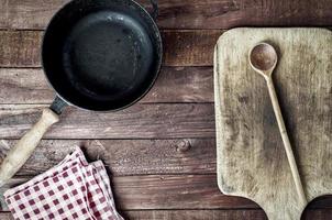 empty black metal pan and cutting board on a wooden surface photo