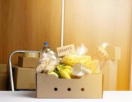 caja de cartón con varios productos, frutas, pasta, aceite de girasol en botella de plástico y conservación. foto