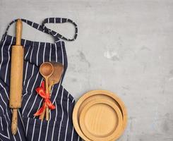 blue striped chef apron, wooden utensils on gray background photo