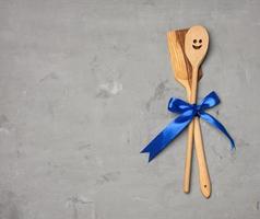 spoon and spatula tied with blue ribbon on gray background photo