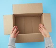 female hands are holding an empty open box of brown cardboard photo