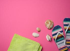 women's multicolored slippers and seashell on pink background photo