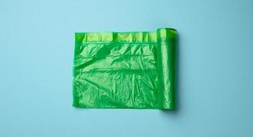 rollo de bolsas de plástico transparentes verdes para papelera sobre fondo azul foto