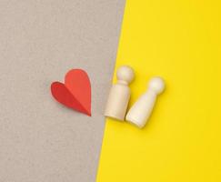 pair of wooden men of the bride and groom and red heart, yellow background, photo