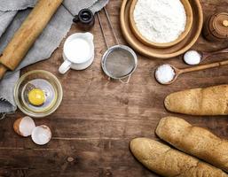 white wheat flour in a wooden bowl and baked baguettes photo