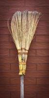 broom on a wooden handle stands near a brick wall photo