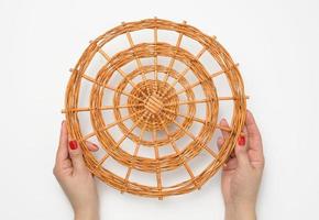 two female hands holding a brown wicker stand on a white background photo