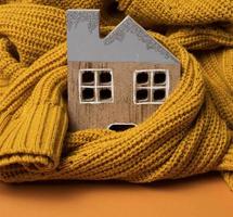 wooden model of the house is wrapped in a warm knitted sweater. Loan concept for house insulation, alternative energy photo