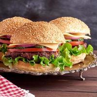 burger with fried cutlet, cheese and vegetables in a round wheat flour bun photo