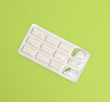 rectangular pieces of gum in a blister pack on a green background photo