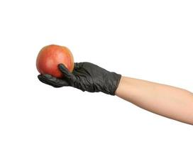 mano femenina en guante de látex negro sostiene manzana roja madura foto