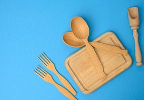 wooden spoons, forks and rectangular cutting board on a blue background photo