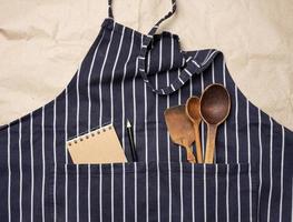 blue chef's apron, inside a pocket of wooden spoons photo