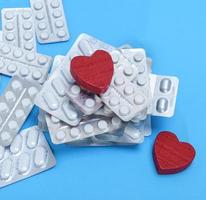 a stack of different pills in a package and two red hearts photo