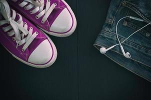 Sports shoes and a fragment of jeans on a black wooden background, vintage toning photo