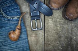 Detail of worn blue jeans and brown shoes on a wooden background photo