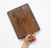 female hand with red manicure holds blank old vintage rectangular kitchen chopping board photo