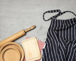 blue striped chef apron, wooden utensils on gray background photo