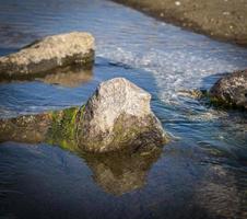 piedra que sobresale del mar agua día de verano foto