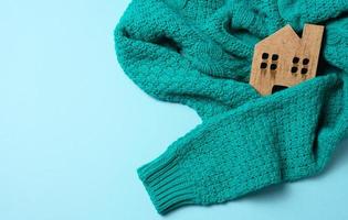 brown wooden model of the house is wrapped in a warm knitted sweater. Loan concept for house insulation, alternative energy photo