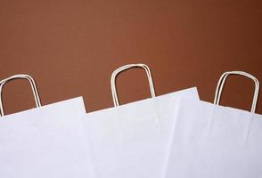 white paper disposable bag with handles on a brown background photo