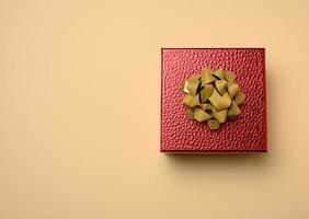 red cardboard box tied with a silk red ribbon on a beige background photo