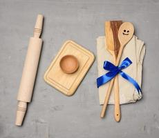 spoon and spatula tied with blue ribbon on gray background and wooden rolling pin photo