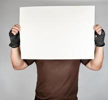 athlete in brown clothes holds a large blank white sheet of paper photo