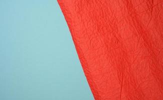 crumpled sheet of red paper on a blue background photo