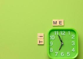 square green alarm clock on a green background and the inscription time photo