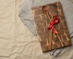 old spoon and spatula tied with red ribbon on a brown paper background photo