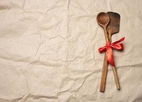 spoon and spatula tied with red ribbon on a brown paper background photo