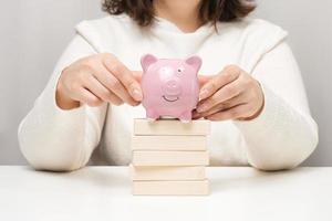 pink ceramic piggy bank and wooden blocks. Concept of increasing interest on a deposit in a bank, high return on investment, large margin on sale photo