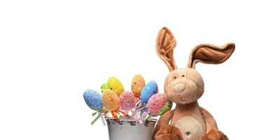 teddy bunny sitting on a white background and decorative colorful easter eggs photo