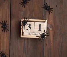 figuras de araña negra y reloj retro de madera hecho de bloques con la fecha del 31 de octubre foto