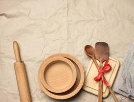 spoon and spatula tied with red ribbon on a brown paper background and wooden rolling pin photo
