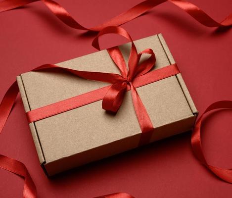 Overhead shot of multiple simple, lidded boxes tied with red raffia ribbon  bows and string. One has a blank tag for your message. Oak plank table bel  Stock Photo - Alamy