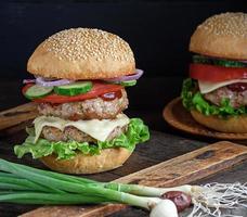 burger with two fried cutlets, cheese and vegetables photo