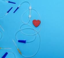 empty plastic dropper with needles and red heart on blue background, medical device photo