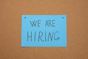 blue sheet of paper with an inscription on a brown cork board. Recruitment concept, vacancy photo