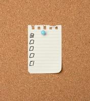 blank sheet of paper in a line attached with a plastic button on a brown cork board photo